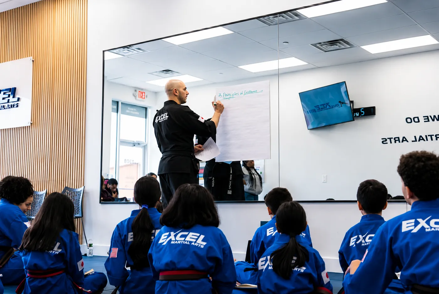 Sensei Hany writing the Principles of Excellence for students at Excel Martial Arts